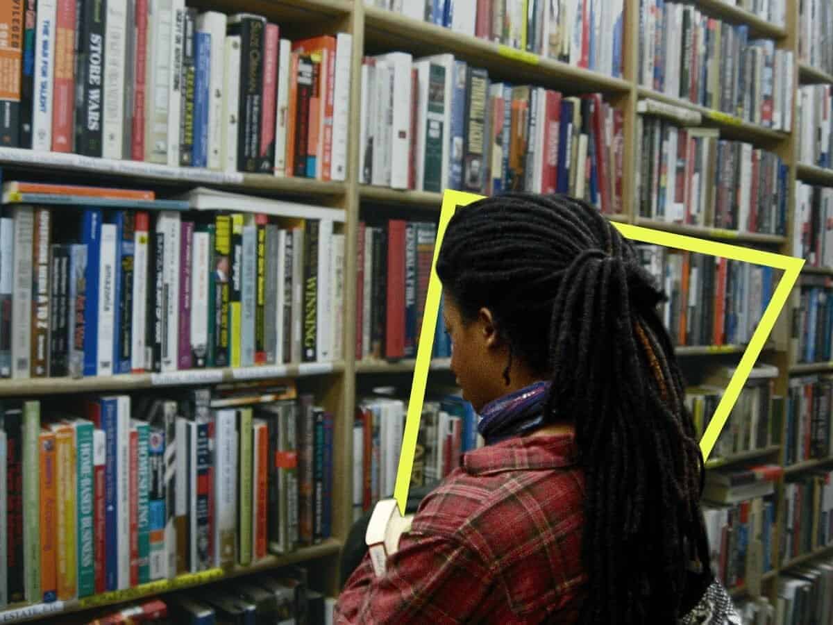 Young girl in a library looking at books on a shelf
