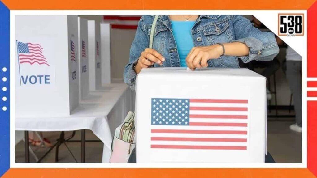 A woman putting a ballot in a ballot box with an american flag on the front