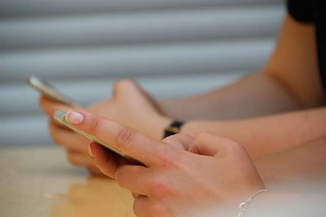 Teens-on-social How children and teens should use social media teen hands holding cell phones at a school desk