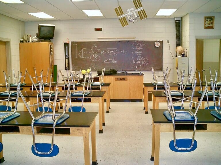 Keep them stupid a high school classroomsith chairs up on desks to clean the floor