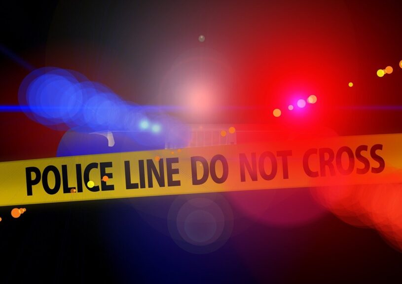 Violent crime. Blurry police car lights in the background behind yellow crime tape
