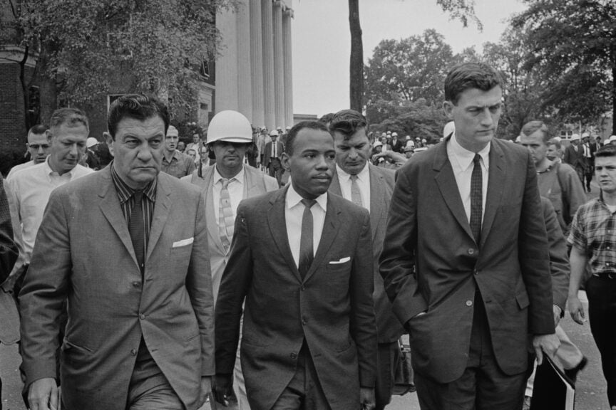 James meredith walking into an all-white school in mississippi flanked by u. S. Marshals.
