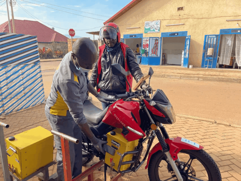 Two people standing looking down at a motorcycle