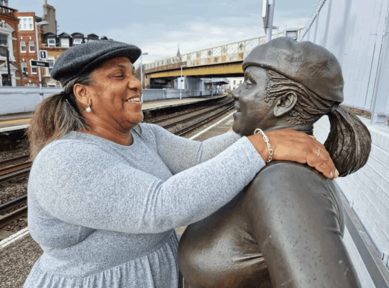Woman with her arms over the shoulders of a statue of women